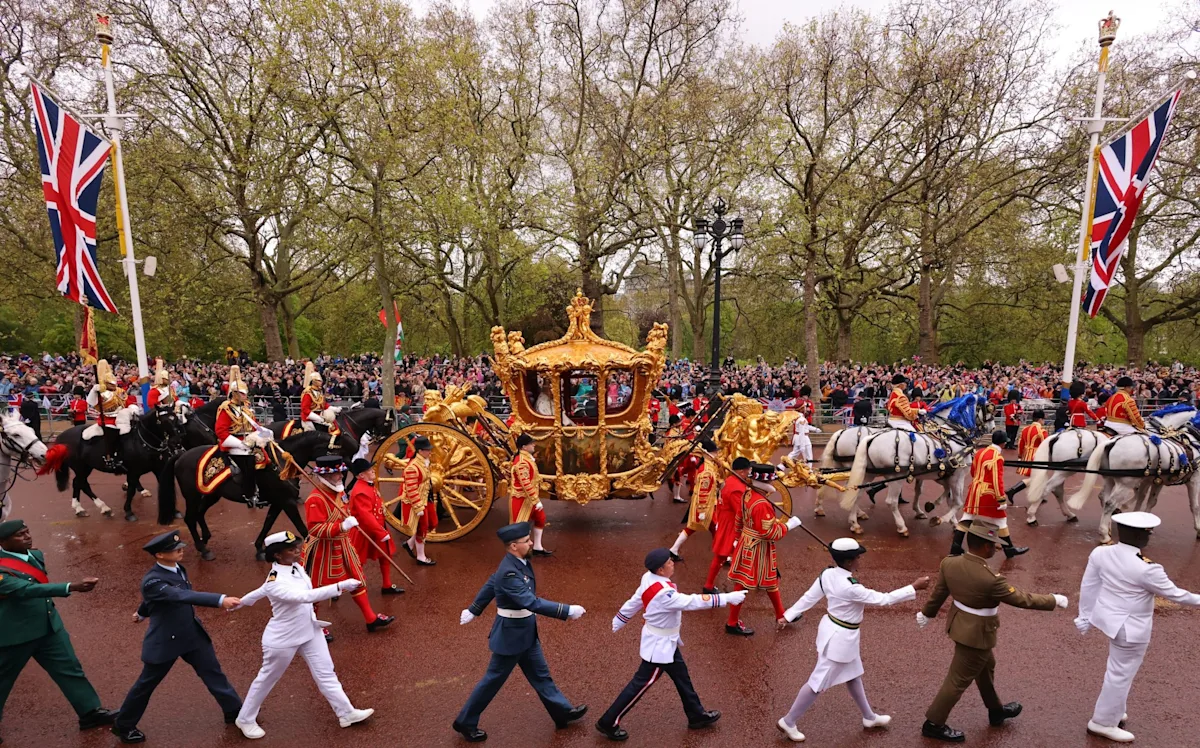 The BBC logo on a screen with a red axe symbol over it, representing the cutting of the crown jewel of British broadcasting, with a subtle background image of a TV studio